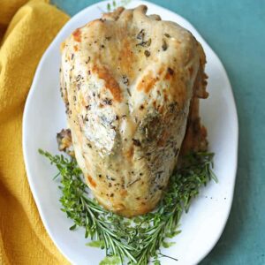 slow cooker turkey crown on platter with herbs.