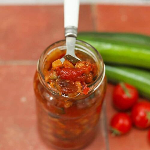 jar of courgette and tomato chutney with spoon.
